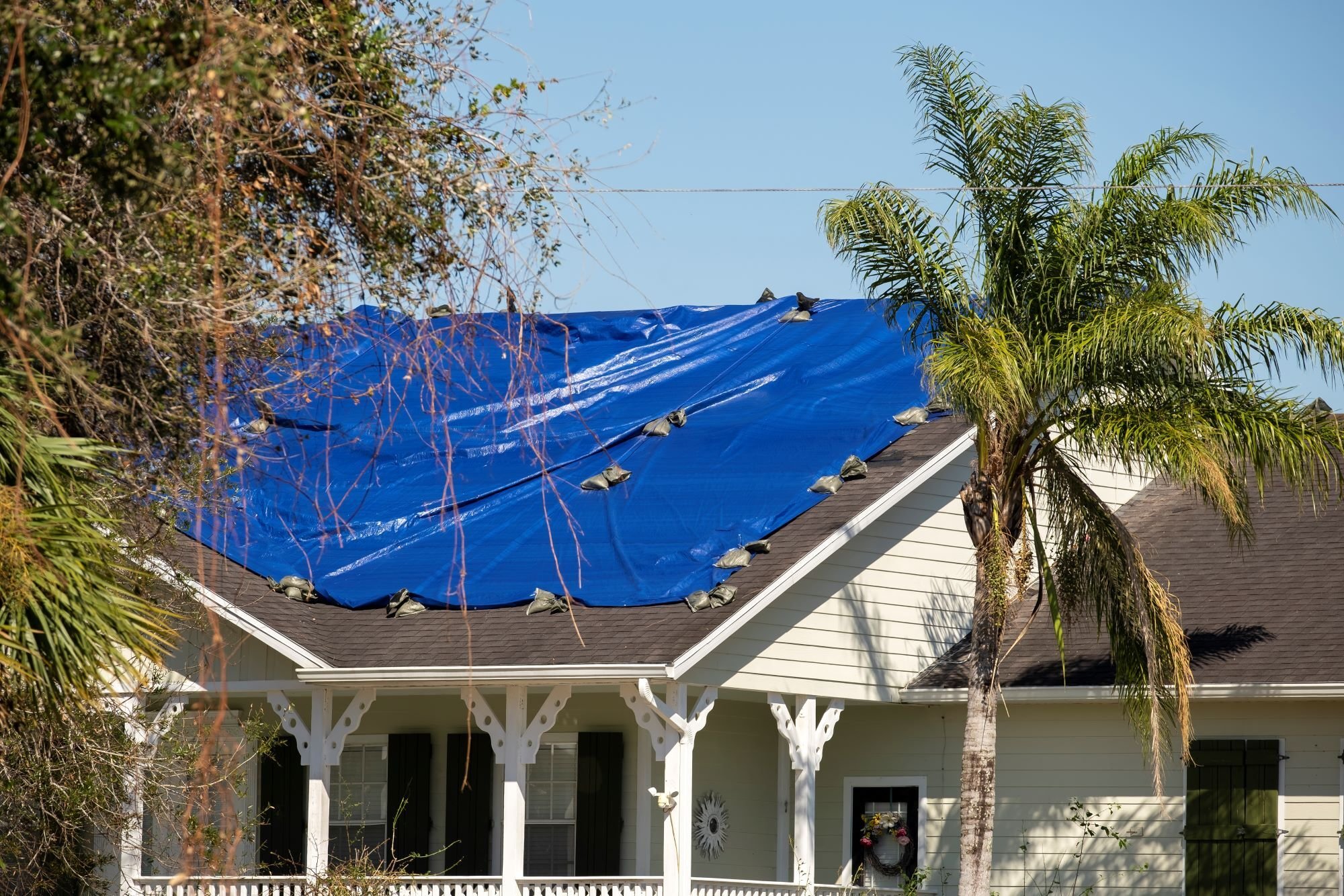 damaged-in-hurricane-house-roof-covered-with-blue-2024-12-06-05-01-07-utc-1